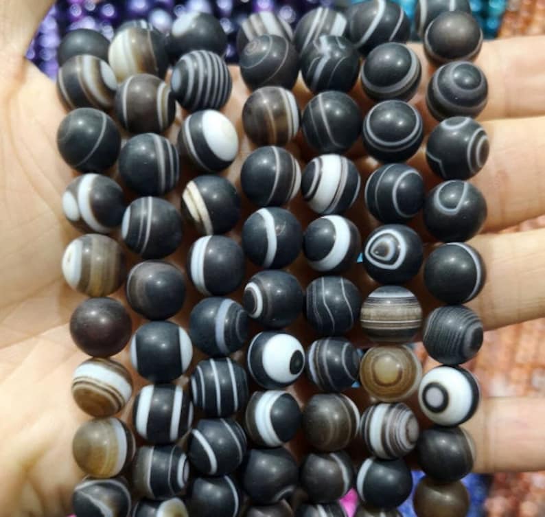May include: A strand of black and white agate beads. The beads are round and have a polished finish. The agate has a natural pattern of white and black stripes.