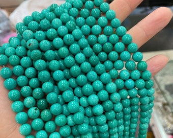 May include: A strand of turquoise beads, each bead is round and smooth, with a light green color. The beads are strung together on a clear thread.
