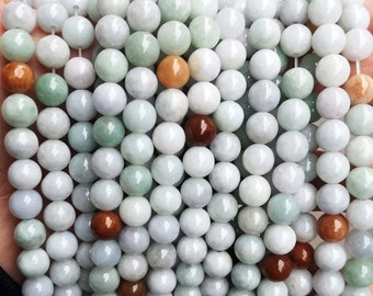 Puede incluir: Una hebra de cuentas de jade redondas y lisas en varios tonos de verde, blanco y marrón. Las cuentas tienen un diámetro aproximado de 8 mm y un acabado pulido.