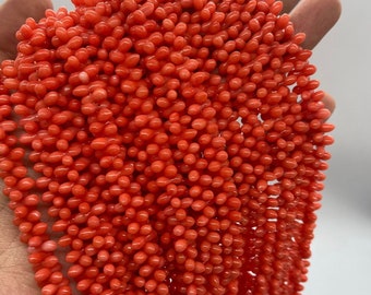 May include: A strand of bright orange coral beads, each bead is a small, elongated oval shape.