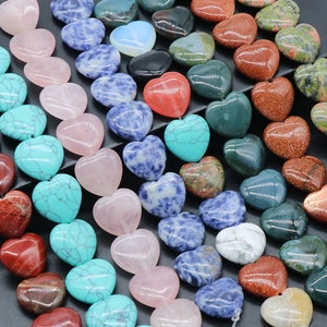 Könnte beinhalten: Sortiment an herzförmigen Edelsteinperlen in verschiedenen Farben, darunter rosa, blau, grün, rot und braun. Die Perlen sind aus natürlichen Steinen gefertigt und perfekt für die Schmuckherstellung.