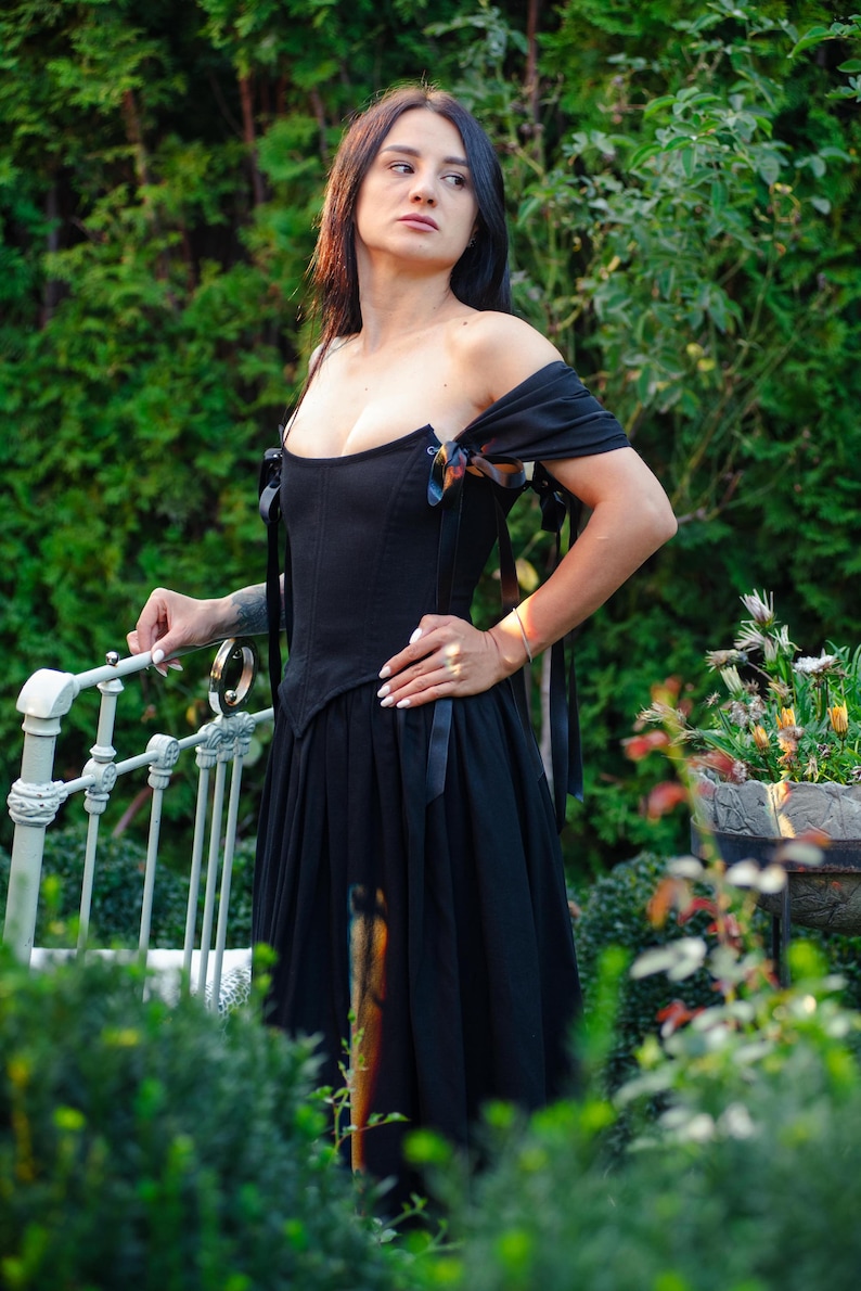Black Victorian corset dress with tiered skirt and dramatic bustle detail.