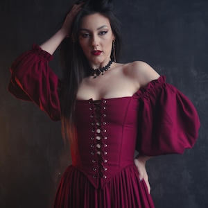 Renaissance burgundy corset dress with puff sleeves and flowing skirt