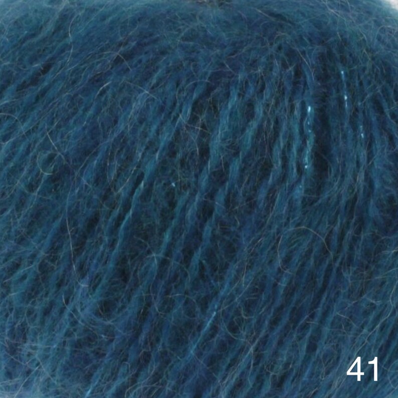 May include: A skein of teal blue yarn with a fuzzy texture. The yarn is made of a blend of mohair and silk.