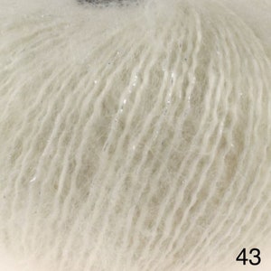 May include: A close-up of a skein of white yarn with a subtle shimmer. The yarn is soft and fluffy, and it has a delicate texture.