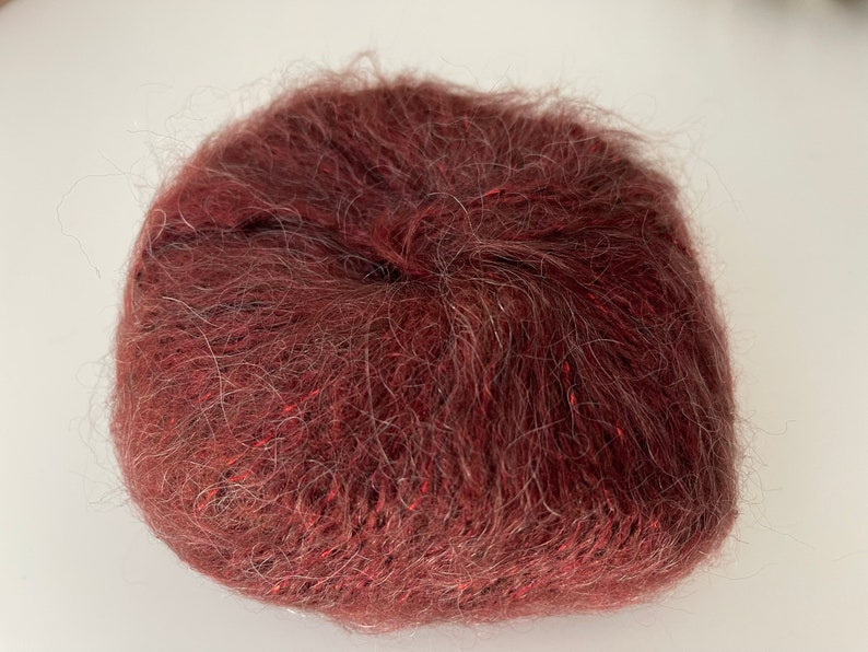 May include: A ball of deep red yarn with a fuzzy texture.