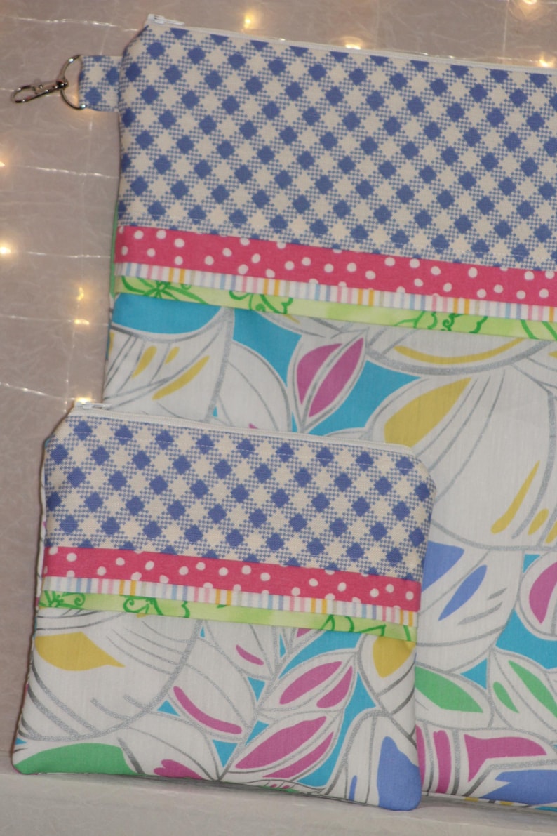 Puede incluir: Dos estuches con cremallera con un estampado floral y geom&eacute;trico. La parte superior de los estuches presenta un dise&ntilde;o a cuadros azul y blanco. Debajo, se ven una cinta rosa de lunares y una cinta verde. El estuche m&aacute;s grande tiene un cierre plateado.