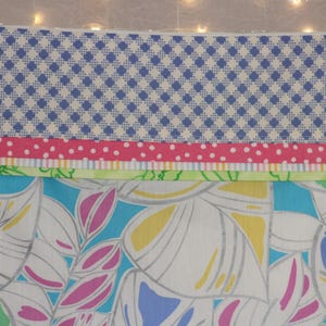 Puede incluir: Una bolsa rectangular con cremallera con una variedad de telas estampadas. La secci&oacute;n superior presenta un patr&oacute;n de cuadros azules y blancos, seguido de una franja rosa de lunares, una franja verde y un dise&ntilde;o floral con hojas azules, rosas y amarillas.