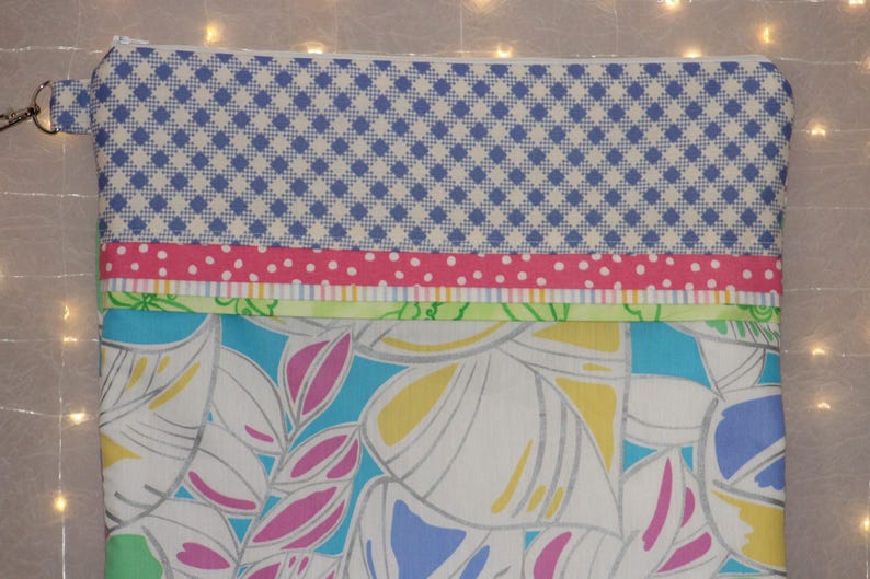 Puede incluir: Una bolsa rectangular con cremallera con una variedad de telas estampadas. La secci&oacute;n superior presenta un patr&oacute;n de cuadros azules y blancos, seguido de una franja rosa de lunares, una franja verde y un dise&ntilde;o floral con hojas azules, rosas y amarillas.