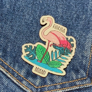 May include: A pink flamingo with a green tropical leaf design, a white background, and the text "Florida" and "Miami" on the patch.