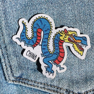 Puede incluir: Un parche bordado para planchar de un dragón azul y rojo con la palabra "CHINA" en blanco.