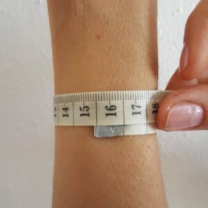 May include: A white measuring tape wrapped around a person's wrist, showing a measurement of 16 inches.