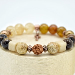 May include: A multi-colored beaded bracelet with brown, black, white, and orange beads. The bracelet has a copper clasp.