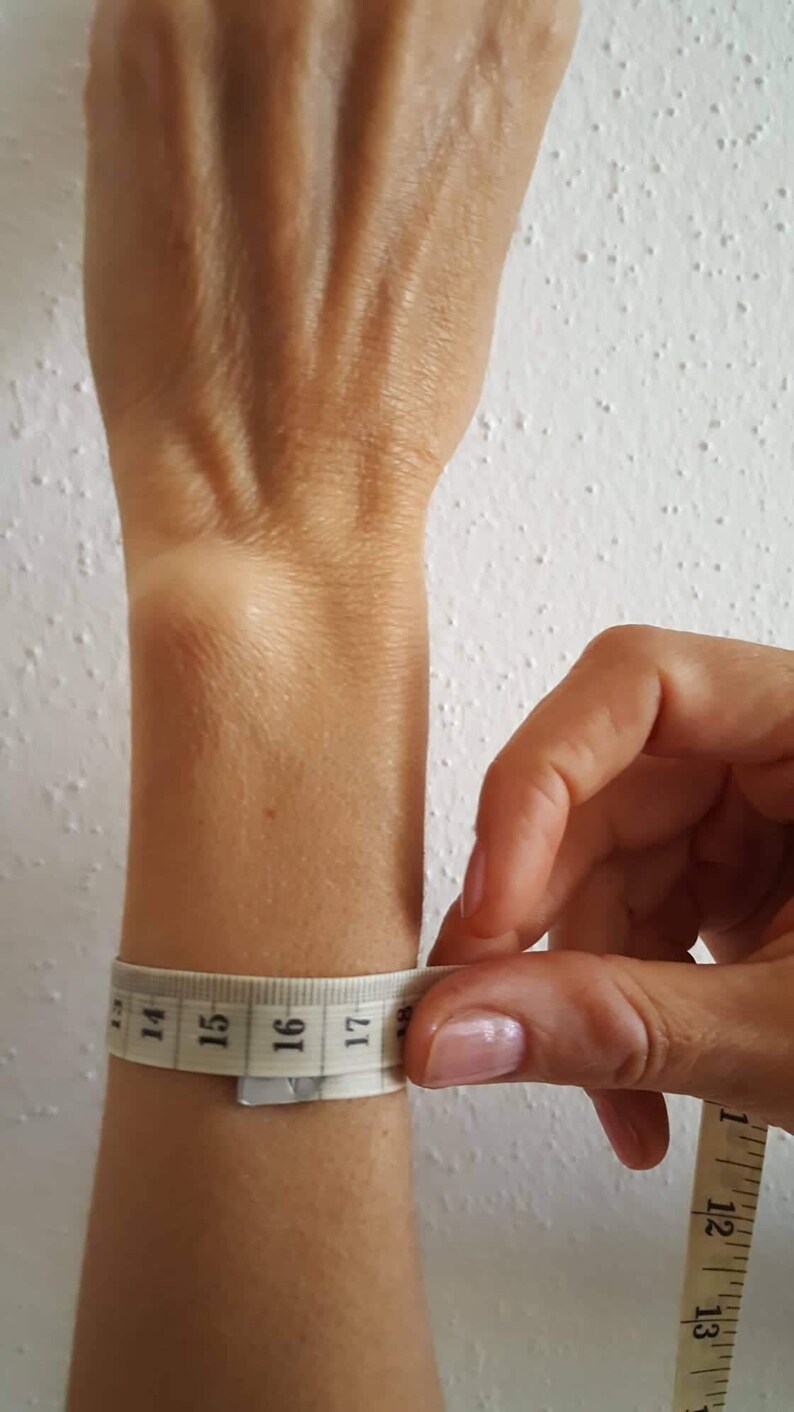 May include: A white measuring tape wrapped around a person's wrist, showing a measurement of 16 inches.