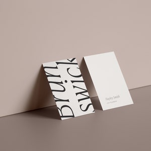 May include: Two white business cards, one with a black and white graphic design featuring the word "black" repeated in a stylised font and the other with the text "Hayley Smith, Creative Director".