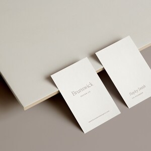 May include: Two white business cards on a light brown surface. The top card has the text "Brunswick Design Co." The bottom card has the text "Hayley Smith Co-Founder".
