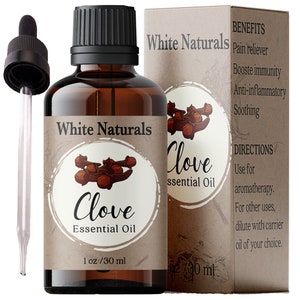 Puede incluir: Una botella de vidrio marrón con un gotero llena de aceite esencial de clavo. La botella tiene una etiqueta blanca con el texto "White Naturals Clove Essential Oil 1 oz/30 ml". La botella está al lado de una caja de cartón marrón con el texto "White Naturals Clove Essential Oil" y una lista de beneficios e instrucciones de uso.