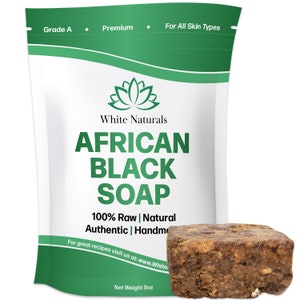 Può includere: Un sacchetto bianco con testo verde che recita "Grade A", "Premium", "For All Skin Types", "White Naturals", "AFRICAN BLACK SOAP", "100% Raw | Natural", "Authentic | Handmade", "For great recipes visit us at: www.White", e "Net Weight 8oz". Una saponetta marrone è in primo piano.