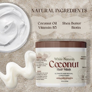 May include: White Naturals Coconut Hair Mask, a white jar with a brown lid, is labeled with the product name and ingredients: Coconut Oil, Shea Butter, Vitamin B5, and Biotin. The jar is 8.8 ounces (250 grams) and is infused with coconut oil. The jar is sitting on a light brown surface.