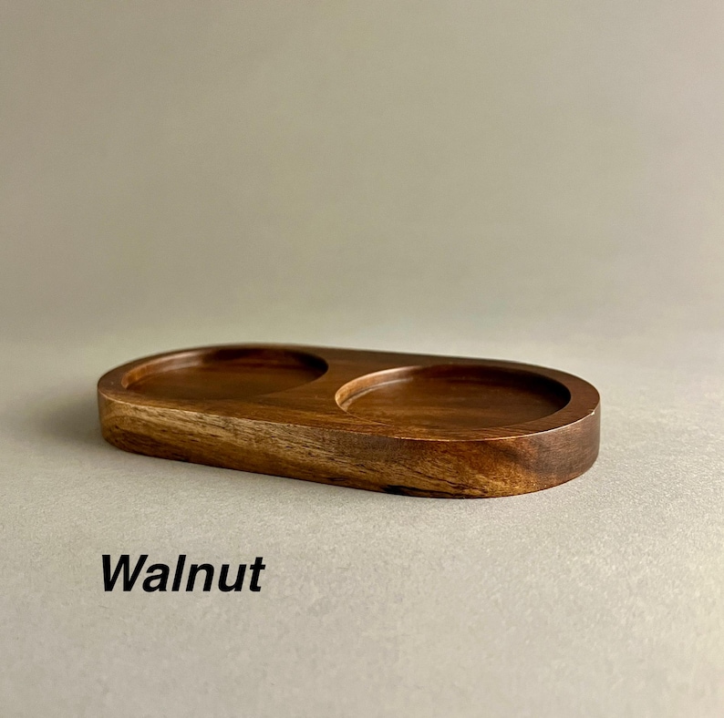 May include: A wooden serving tray with two circular depressions. The tray is made of walnut wood and has a natural finish.