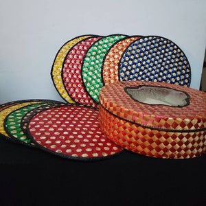 May include: A set of colorful woven round coasters with a matching woven box with a clear lid. The coasters are in shades of red, orange, yellow, green, and blue.