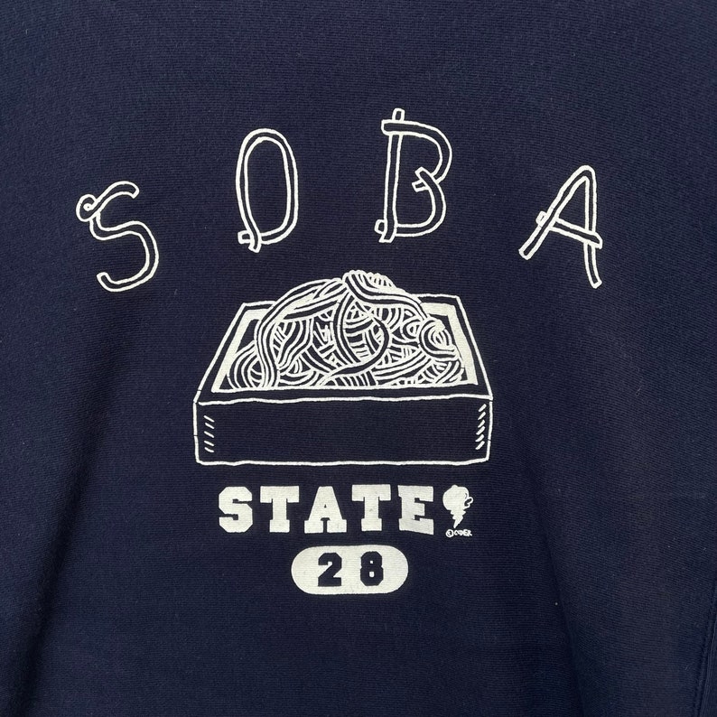 May include: A navy blue sweatshirt with a white graphic of a bowl of noodles and the text "SOBA STATE 28".