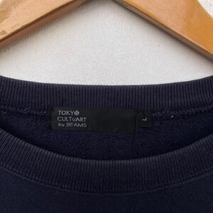 May include: A navy blue sweatshirt with a black tag that reads "TOKYO CULTUART by BEAMS" and a size label that says "L".