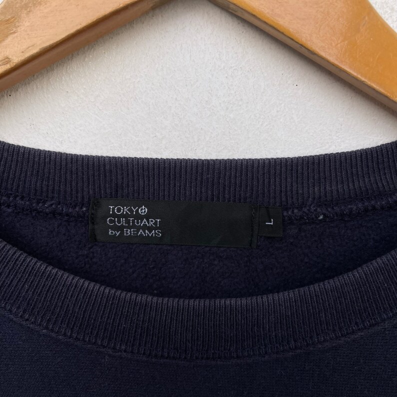 May include: A navy blue sweatshirt with a black tag that reads "TOKYO CULTUART by BEAMS" and a size label that says "L".