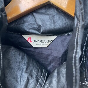 May include: A black jacket with a white label that reads "AL ANDRELUCIAN vesta quest' al"