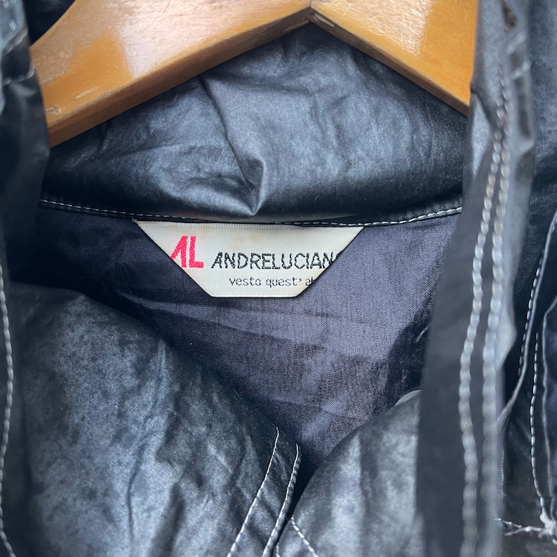 May include: A black jacket with a white label that reads "AL ANDRELUCIAN vesta quest' al"