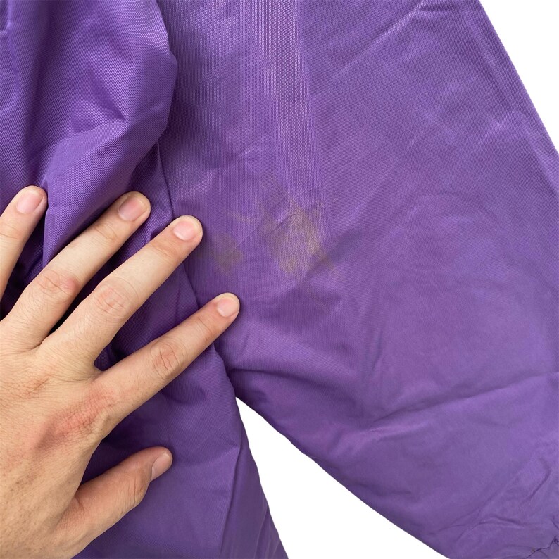 May include: Purple nylon jacket with a slight stain on the sleeve.