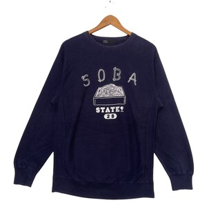 May include: A navy blue sweatshirt with a white graphic of a box of noodles and the text "SOBA STATE? 20".