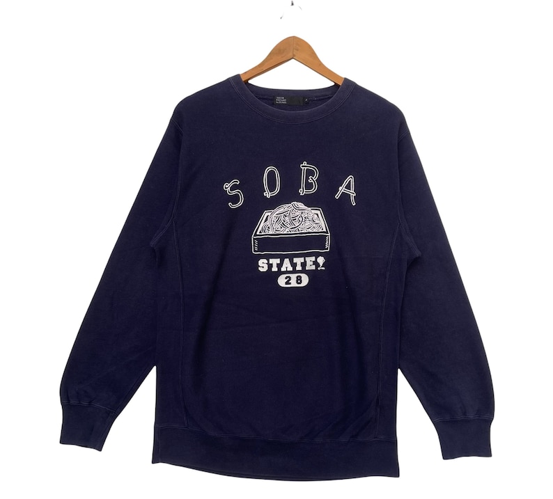 May include: A navy blue sweatshirt with a white graphic of a box of noodles and the text "SOBA STATE? 20".