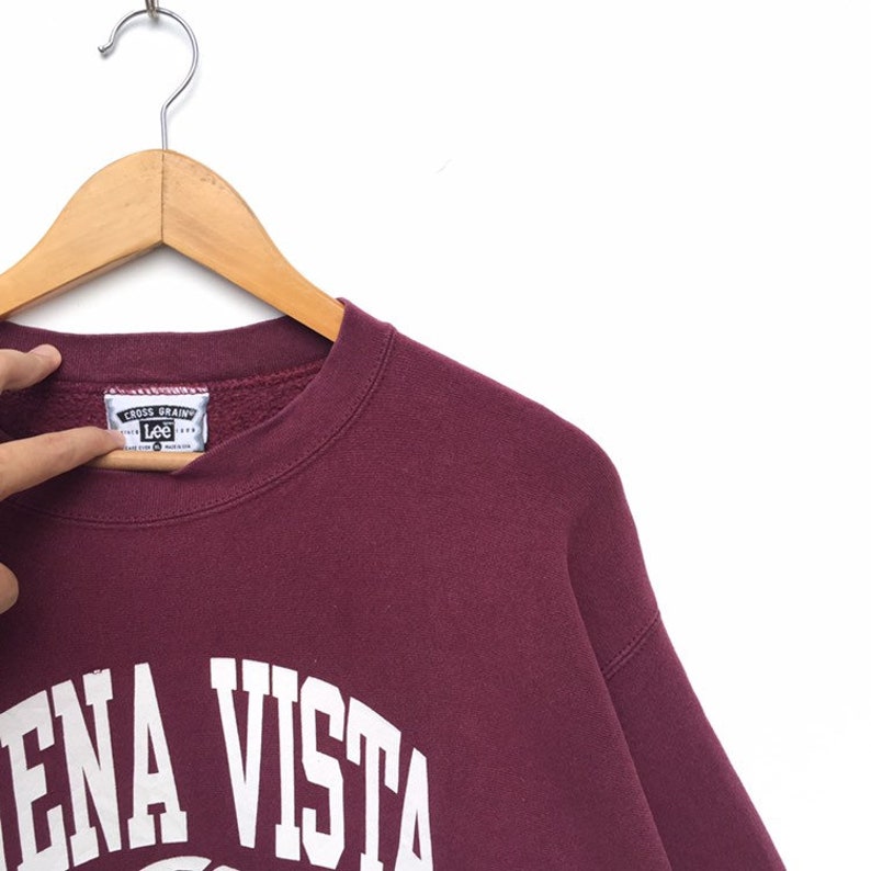 May include: Burgundy sweatshirt with white lettering that reads "Lena Vista" on the front. The sweatshirt has a Lee label with the text "Cross Grainy" on it.