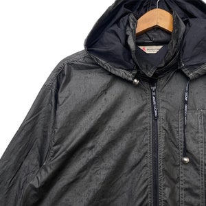 May include: A black hooded jacket with a zip fastening and two pockets. The jacket has the text "ANDRE LUCIANO" printed on the front and back.