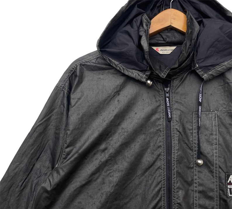 May include: A black hooded jacket with a zip fastening and two pockets. The jacket has the text "ANDRE LUCIANO" printed on the front and back.