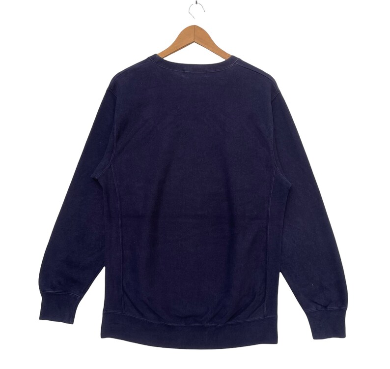 May include: A navy blue sweatshirt with long sleeves and a crew neck.