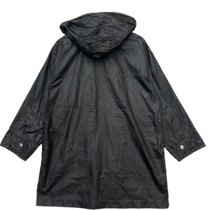 May include: A black hooded jacket with a zip fastening and two pockets on the front. The jacket is made from a lightweight, water-resistant material.
