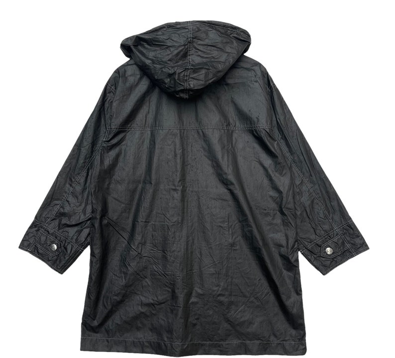 May include: A black hooded jacket with a zip fastening and two pockets on the front. The jacket is made from a lightweight, water-resistant material.