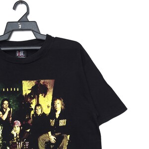 May include: Black t-shirt with a band graphic featuring five people in front of a palm tree and the text "Giant".