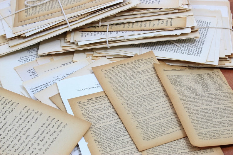 Pode incluir: Uma pilha de p&aacute;ginas de livros velhos, amarelados e desgastados com texto de uma hist&oacute;ria intitulada "Os Tr&ecirc;s Mosqueteiros".