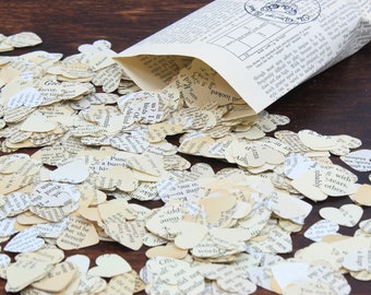 May include: A brown paper bag filled with heart-shaped confetti made from recycled book pages. The confetti is scattered on a wooden surface.