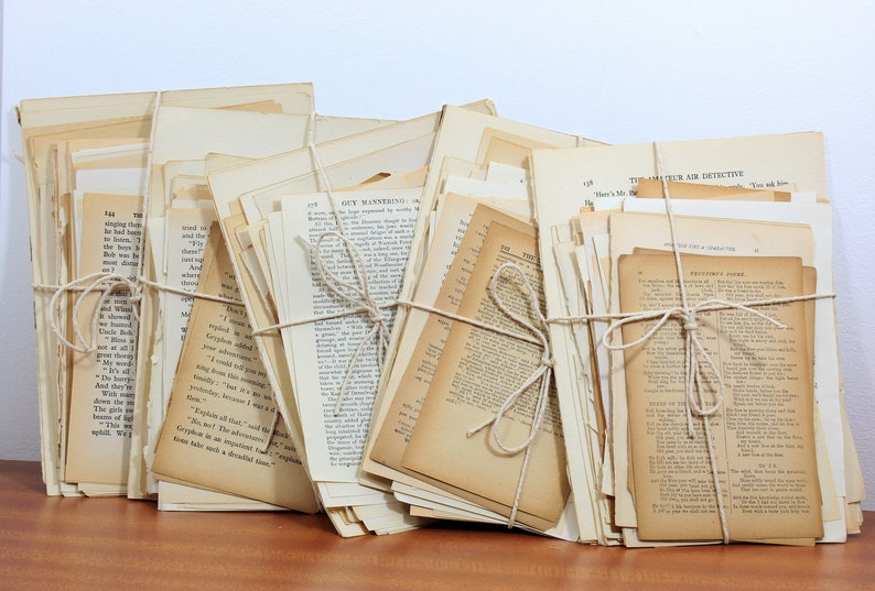 Pode incluir: Uma pilha de p&aacute;ginas de livros antigos amarradas com barbante. As p&aacute;ginas s&atilde;o de cor creme e t&ecirc;m texto preto impresso nelas. As p&aacute;ginas est&atilde;o dispostas em ordem aleat&oacute;ria e algumas das p&aacute;ginas t&ecirc;m vincos e rasgos vis&iacute;veis.