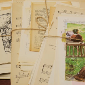May include: A stack of vintage paper ephemera, including sheet music, book pages, and illustrations, tied together with twine. The paper is cream-coloured and has a distressed, aged look.