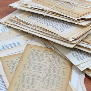 Pode incluir: Uma pilha de p&aacute;ginas de papel velhas, amareladas e desgastadas com texto impresso nelas. As p&aacute;ginas est&atilde;o amarradas com um barbante. As p&aacute;ginas est&atilde;o dispostas em uma pilha, com algumas p&aacute;ginas que sobressaem dos lados. As p&aacute;ginas est&atilde;o sobre uma superf&iacute;cie de madeira.