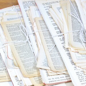 Może przedstawiać: Stos starych, białych kartek papieru związanych białym sznurkiem. Kartki pochodzą z książki i mają na sobie wydrukowany tekst. Tekst jest czarnym atramentem i w większości nieczytelny. Kartki są lekko zaż&oacute;łcone od czasu.