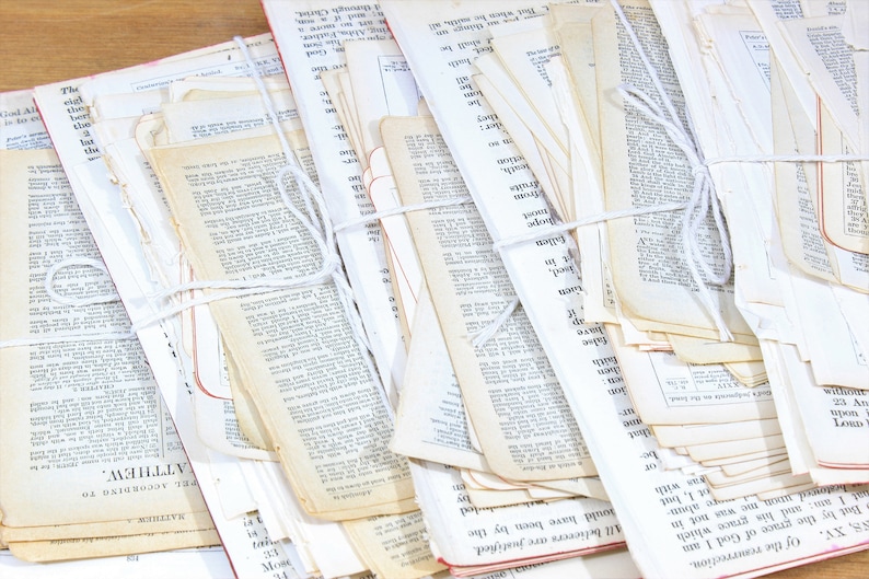 Może przedstawiać: Stos starych, białych kartek papieru związanych białym sznurkiem. Kartki pochodzą z książki i mają na sobie wydrukowany tekst. Tekst jest czarnym atramentem i w większości nieczytelny. Kartki są lekko zaż&oacute;łcone od czasu.