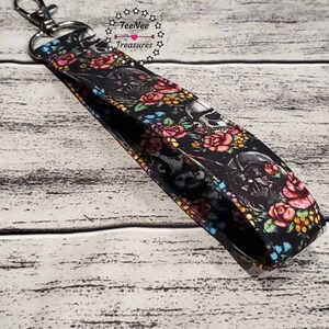 May include: Black and white key chain with a floral and skull design. The key chain has a silver metal key ring. The text "TeeNee Treasures" is printed on the key chain.