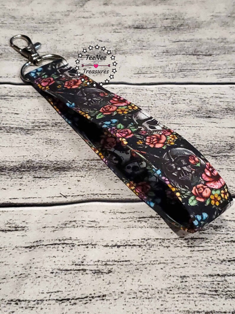 May include: Black and white key chain with a floral and skull design. The key chain has a silver metal key ring. The text "TeeNee Treasures" is printed on the key chain.