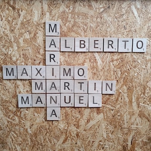 May include: A wooden board with the names "Alberto", "Maximo", "Martin", and "Manuel" spelled out in letter tiles.